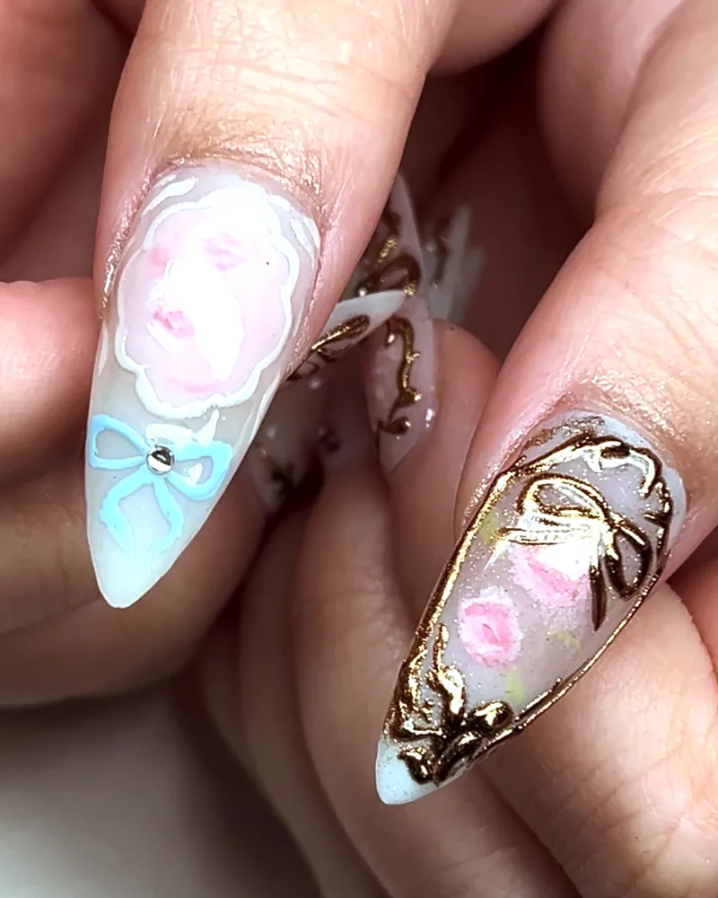 Fairy princess nails: a pink rose and blue bow painted on long almond nails with gold chrome